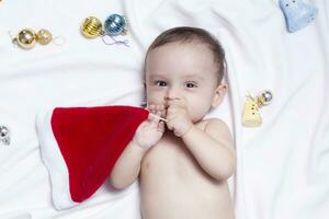 9 månad bebis pojke med santa claus hatt. jul morgon. liten unge spelar. foto