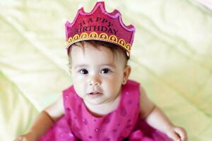 först födelsedag. liten glad bebis flicka med krona fira henne först födelsedag fest foto