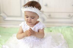bebis flicka i vit klänning tar en skön enda vit blomma foto
