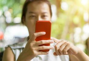 fokus hand av ung asiatisk kvinna rörande röd smartphone foto