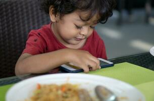 Pojkar do inte äta mat eftersom de spela smartphones foto