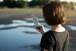 asiatisk kvinna använder sig av smartphone på solnedgång. foto