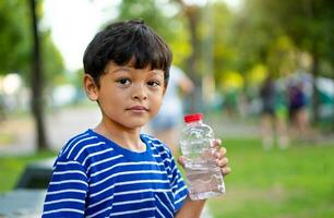 unge törstig vatten och håll transparent plast vatten flaska vatten foto