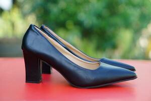 svart läder hög häl skor för kvinna, utomhus- bakgrund. begrepp, modern och artig fotkläder för kontor kvinnor arbetare. tjock häl och smal huvud skor. foto
