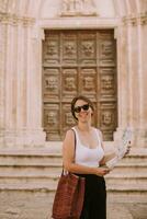 kvinna turist med stad Karta förbi de kyrka san francesco dassisi i ostuni, Italien foto