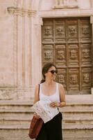 kvinna turist med stad Karta förbi de kyrka san francesco dassisi i ostuni, Italien foto