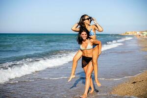 två Söt ung kvinna har roligt på de havet foto