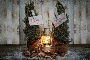 jul hälsning kort hängande från två tall träd mellan en lykta i de snö foto