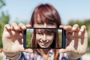Söt kvinna med röd hår ta en selfie med smart telefon foto