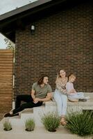 familj med en mor, far och dotter Sammanträde utanför på de steg av en främre veranda av en tegel hus foto