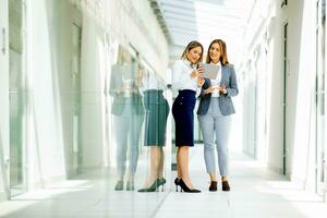 två ung företag kvinnor med digital läsplatta i de kontor hall foto