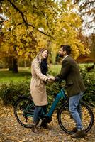 ungt par i höstparken med elektrisk cykel foto