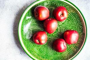 grön keramisk tallrik med röd äpplen foto