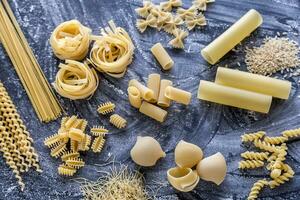 olika typer av pasta på de mörk mjöl dammat bakgrund foto