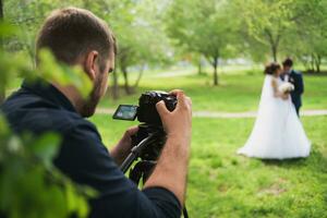 de videographer skjuter de gifta i de trädgård i de sommar. foto