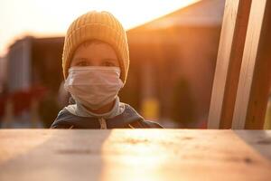 porträtt av en ung barn i en medicinsk mask på de gata under de coronavirus och covid pandemi - 19 foto