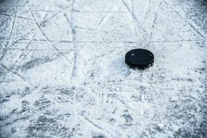 svart hockey puck lögner på is på stadion foto