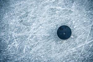 svart hockey puck lögner på is på stadion foto