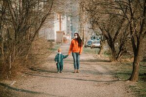 en mor med en bebis i medicinsk masker promenader ner de gata under de coronavirus pandemi och covid -19. foto