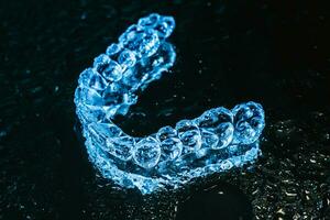 transparent aligners, tand hållare lögn på en spegel med vatten droppar på en svart bakgrund foto