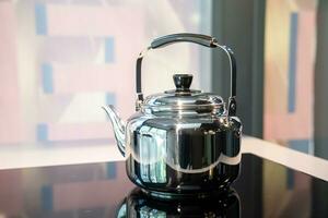 rostfri vatten kråka eller årgång vattenkokare te pott på elektronisk spis i modern kök rum. foto