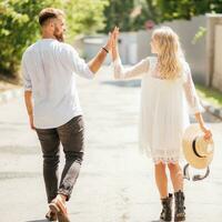 Lycklig och skrattande man och kvinna innehav händer gående längs de väg på en solig dag foto