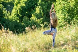 smal kvinna praxis yoga i natur på en solig dag foto