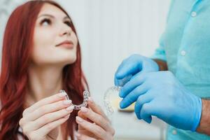 läkare ortodontist visar en kvinna silikon inriktare till räta ut tänder foto