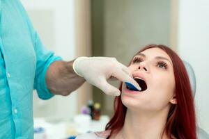 de ortodontist visar de patient ett intryck bricka i som de silikon intryck material kommer vara placerad till skaffa sig de form av henne tänder foto
