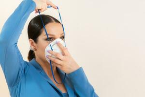 skön flicka sätter på en medicinsk mask på henne ansikte i en Foto studio skydd mot coronavirus och covid-19