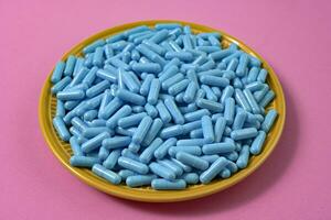 gul tallrik full av blå medicin kapslar representerar läkemedel överdos foto