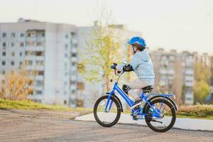 liten unge i hjälm rider en cykel på en solig dag foto