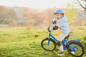 liten pojke i hjälm rider en cykel på en solig dag foto