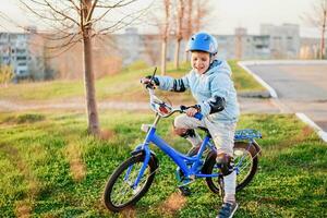 en barn i en hjälm lär till rida en cykel på en solig dag på solnedgång foto