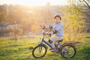 liten pojke i hjälm rider en cykel på en solig dag foto