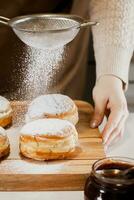 kvinna kock förbereder färsk munkar i henne bageri. matlagning traditionell jewish hanukkah sufganiyot. små företag begrepp. foto