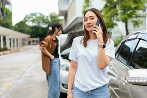 asiatisk kvinnor förare kolla upp för skada efter en bil olycka innan tar bilder och sändning försäkring. uppkopplad bil olycka försäkring krav efter lämna in foton och bevis till ett försäkring företag.