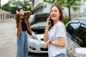 asiatisk kvinnor förare kolla upp för skada efter en bil olycka innan tar bilder och sändning försäkring. uppkopplad bil olycka försäkring krav efter lämna in foton och bevis till ett försäkring företag.