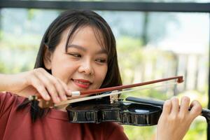 ett attraktiv kvinna inlärning musiker spelar de fiol på Hem. kompositör skapande låtar med sträng instrument. drömmande violinist fingrar brådskande strängar på fiol foto