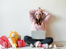 ung kvinna i jultomten som handlar online omgiven av presenter