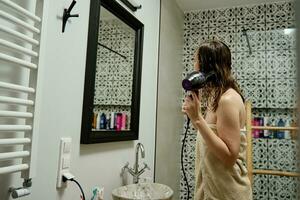 kvinna torkning hårstrån i badrum foto