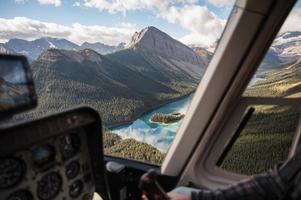 inuti helikoptern som flyger på steniga berg med färgglad sjö foto