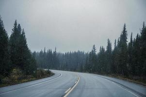 roadtrip på motorväg med snöstorm i barrskog vid Banff National Park foto