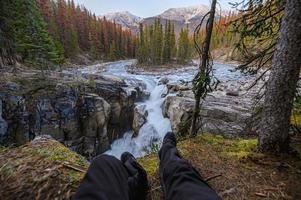 benen resenären sitter och sträcker sig på sunwapta faller i isfält parway vid jasper nationalpark foto