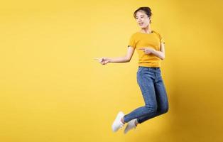 full längd porträtt av glad tjej hoppar upp isolerad på gul bakgrund