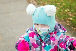 liten flicka pekande finger och leende kirurgisk bandage. coronavirus, sjukdom, infektion, karantän, medicinsk mask, covid19. pojke i en medicinsk mask. karantän och skydd virus, influensa, epidemi covid19. coronavirus karantän. foto