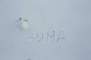 mycket liten snögubbe i snö. kopia Plats. text från ryska vinter- i snö foto