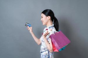 asiatisk kvinna bär kinesisk traditionell klänning med shoppingväska och kreditkort foto