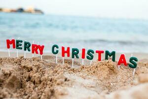 inskrift av glad jul på strand. fira jul på strand. semester på tillflykt i en värma Land innan ny år. foto
