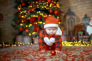 liten överraskad barn i santa kostym i festlig rum på jul eve. flicka på bakgrund av jul träd. foto